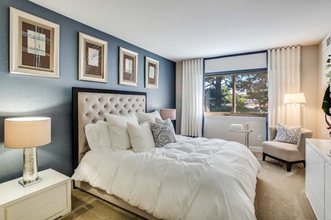 A bedroom with a large bed and a window overlooking a tree.