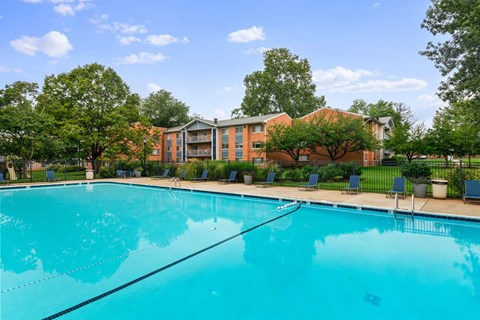 A large swimming pool in front of a building surrounded by trees.