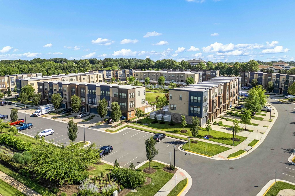 A sunny day at a residential complex with cars parked in the lot.