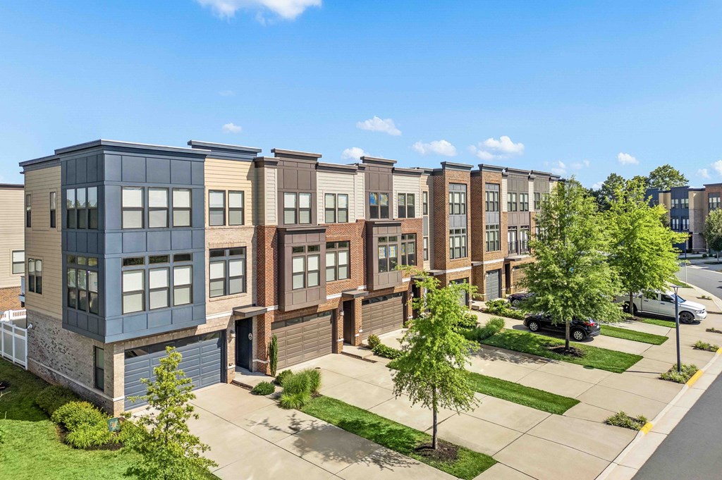 A row of modern townhouses with a clear blue sky above.