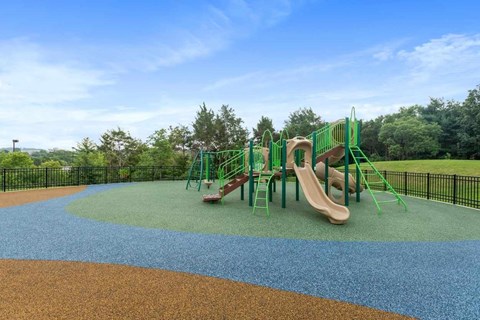 A playground with a slide and plenty of fenced in space.