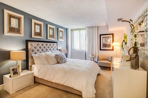 A bedroom with a large bed and a nightstand with a lamp.