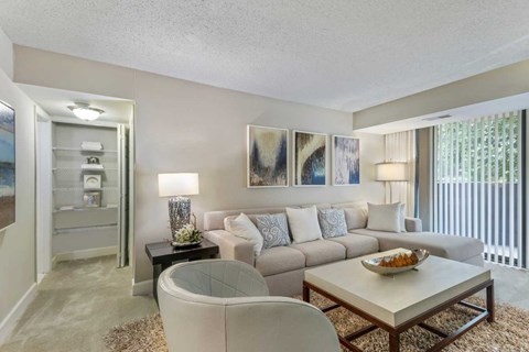 A living room with a white couch, a glass table, and a painting on the wall.