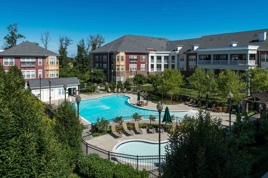 A large swimming pool surrounded by trees and buildings.