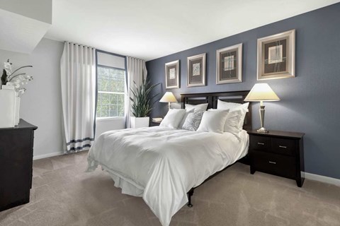A bedroom with a large bed and a window with curtains.