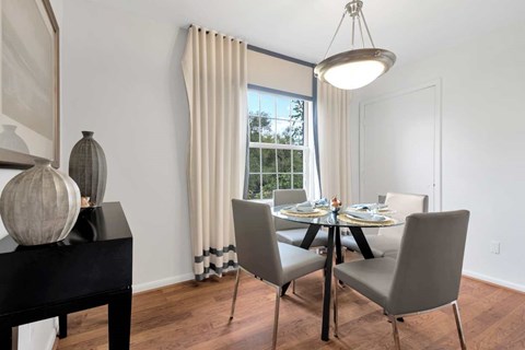 A dining room with a table set for two and a view of the backyard.