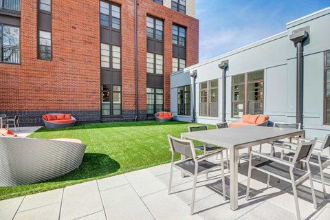 A modern outdoor dining area with a table and chairs.