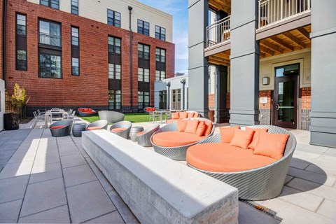 A modern outdoor seating area with orange chairs and a white bench.