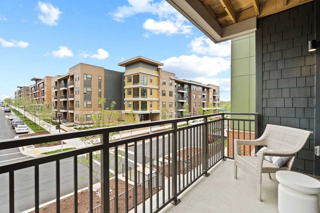 a balcony with a chair and some apartments in the background
