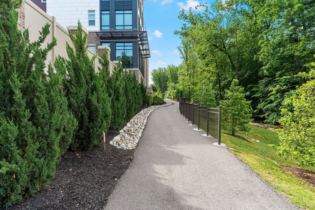 a path in front of a building with trees and a fence