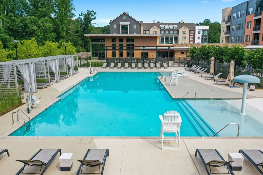 a swimming pool with chairs and a building in the background
