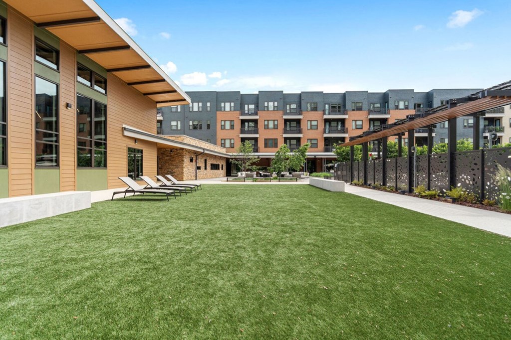 a yard with lawn chairs and a building in the background