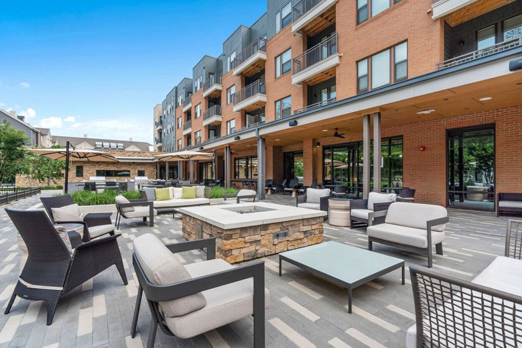 a patio with chairs and tables and a fire pit