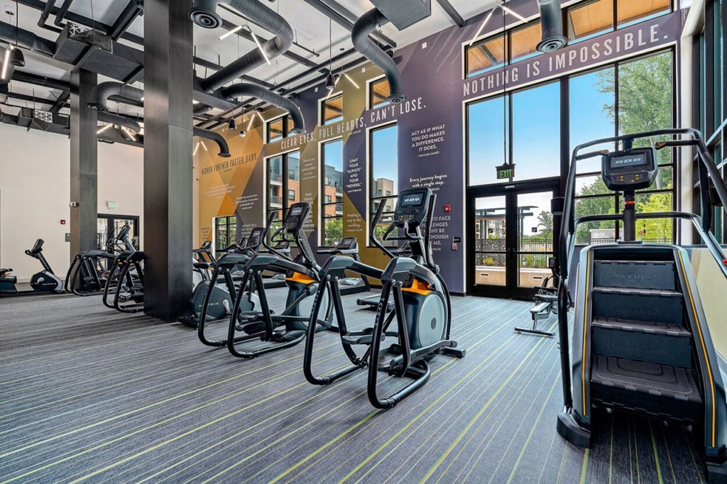 a gym with cardio equipment and weights in a building with glass doors