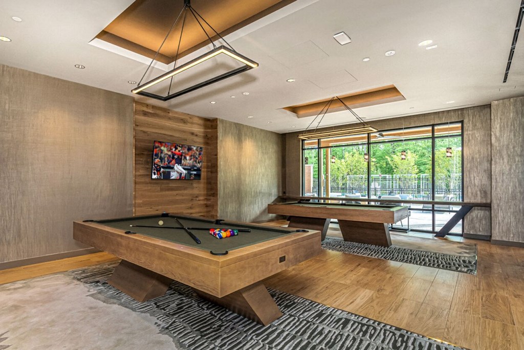 a billiards room with two pool tables and a tv