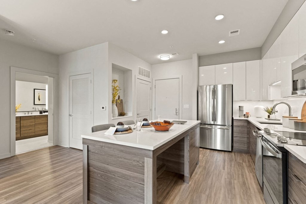 a kitchen with a large island and a stainless steel refrigerator