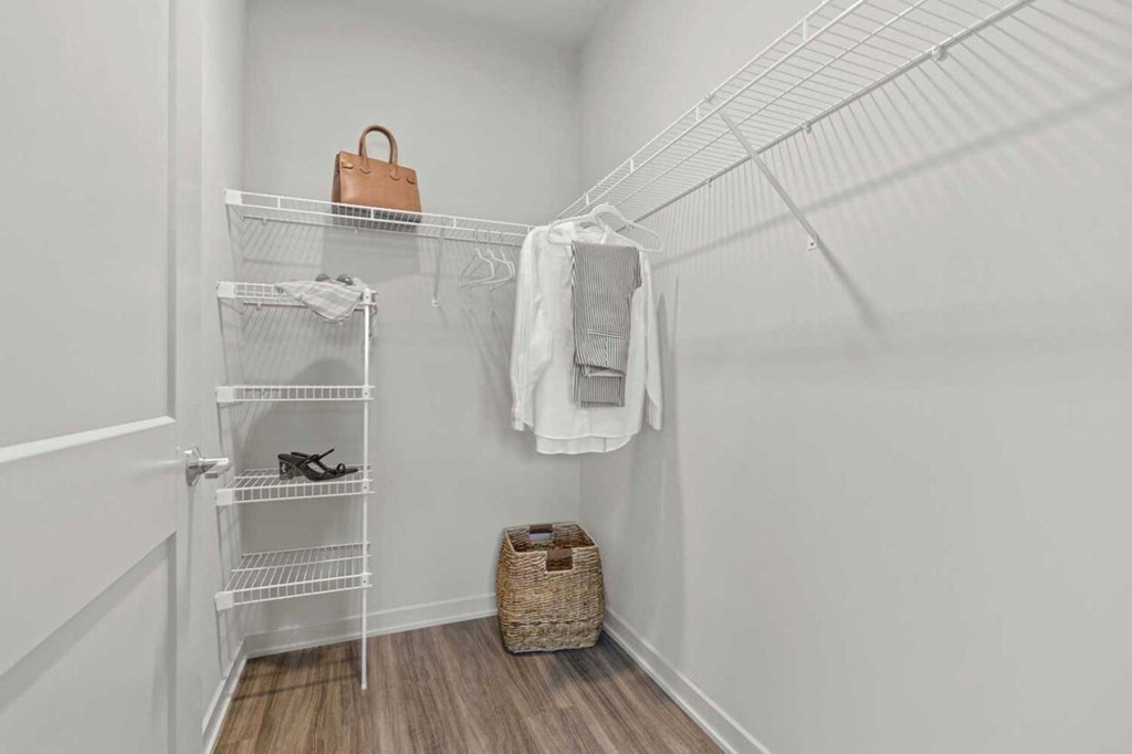 a closet with white walls and a white wardrobe with shelves and a basket
