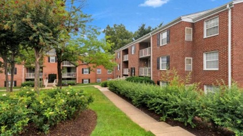 an exterior view of a brick apartment building with a sidewalk