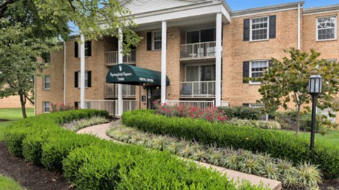 a brick building with a green awning and a garden in front of it