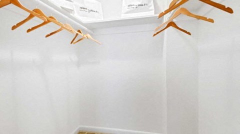 a white closet with wooden shoe racks on the wall