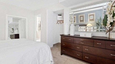 a bedroom with a bed and a dresser and a mirror