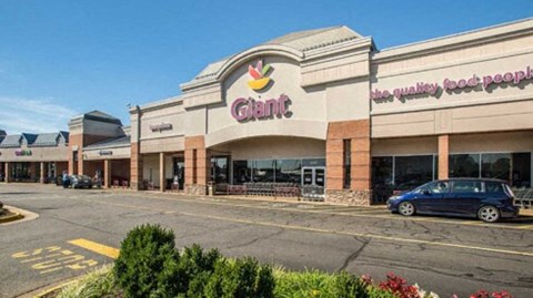 the exterior of a shopping center with a car parked outside