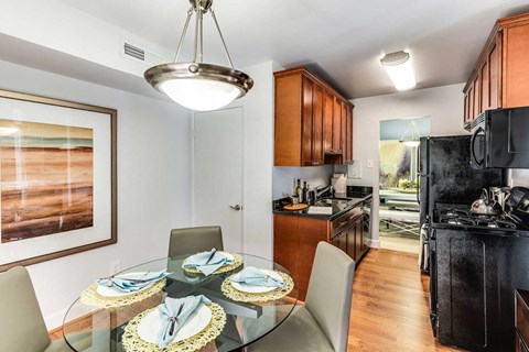 A modern kitchen with a glass dining table set for four.