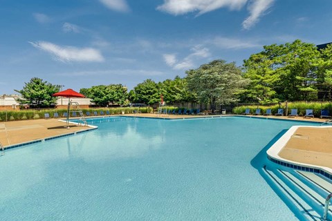 A large swimming pool with a red roof and trees in the background.
