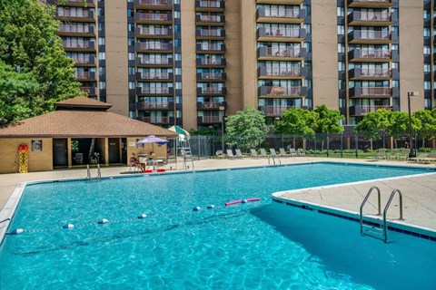 A swimming pool with a diving board and a building in the background.