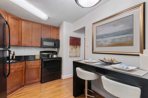 A kitchen with a black counter top and white chairs.