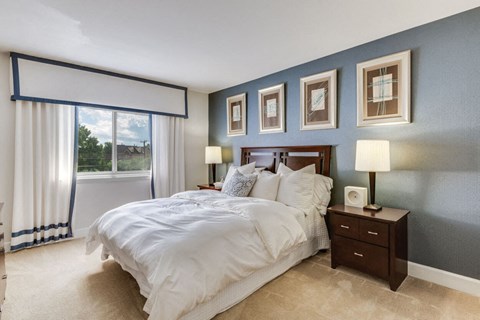 A bedroom with a large bed and a window with curtains.