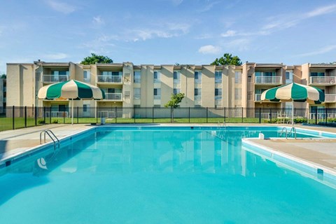 A large swimming pool in front of apartment buildings.