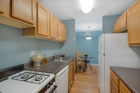 A kitchen with a white stove top oven and wooden cabinets.