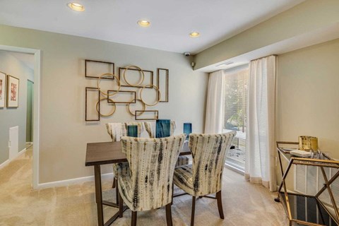 A dining room with a table set for two and a decorative wall piece.