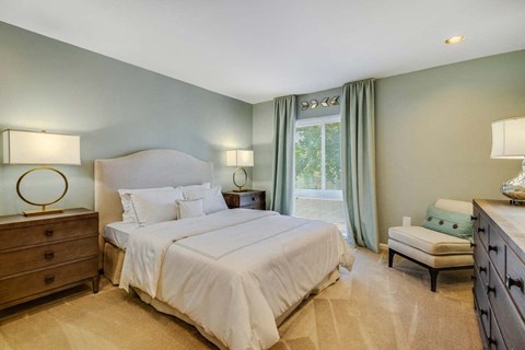 A bedroom with a large bed, two nightstands, and a window with curtains.