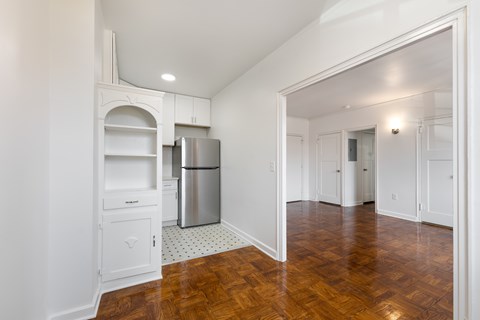 A kitchen with white cabinets and a wooden floor.