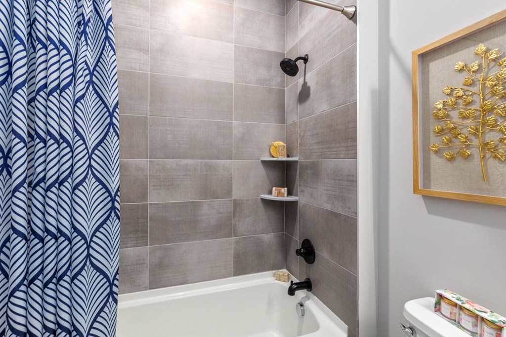 Bathroom with a shower curtain, a tub, a shelf, and a picture at Encore at West Valley, Michigan, 48386