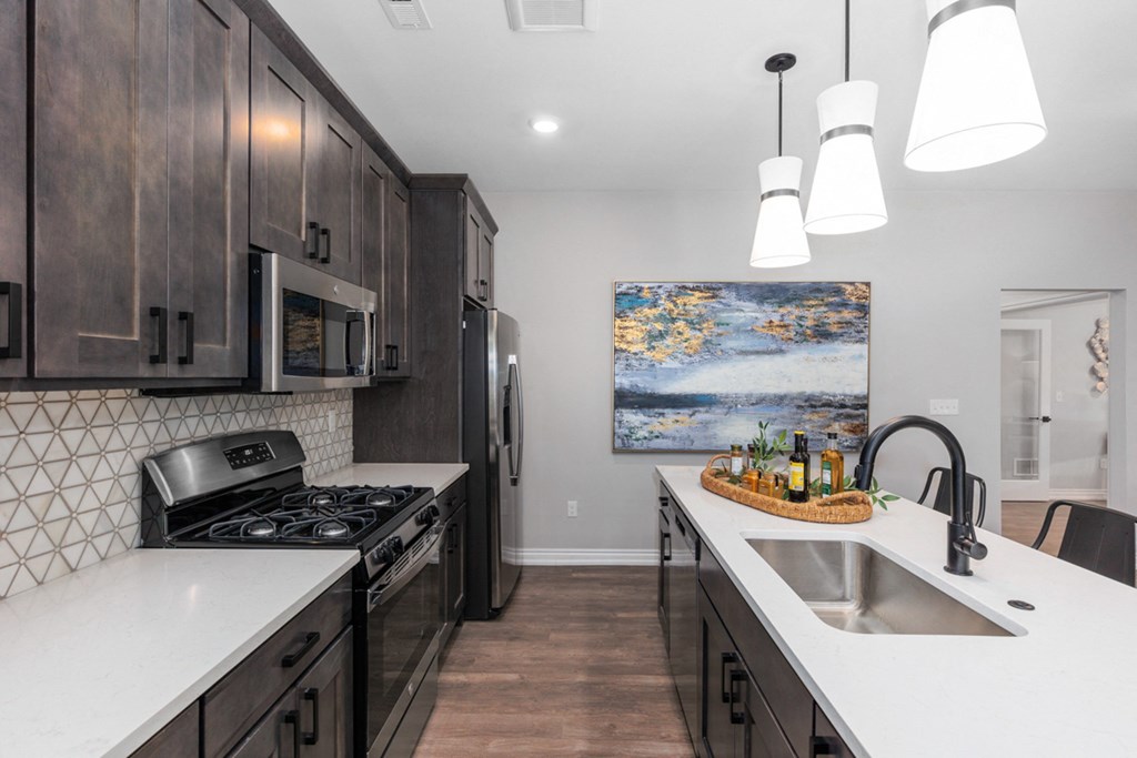 A modern kitchen with dark wood cabinets and white countertops at Encore at West Valley, White Lake, MI, Michigan