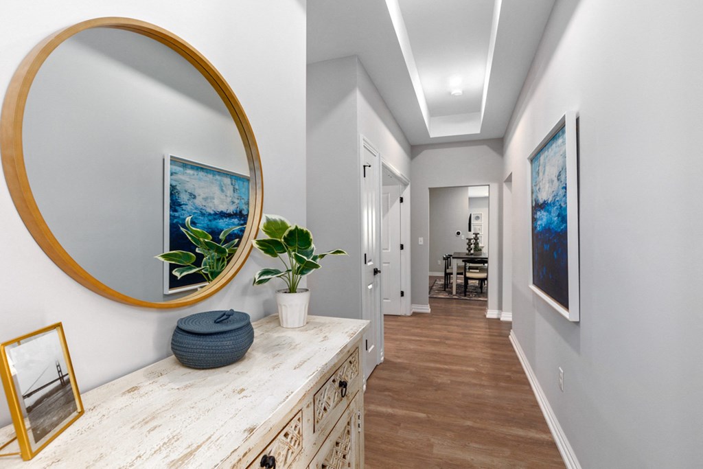 Hallway with a round mirror and a painting on the wall at Encore at West Valley, White Lake