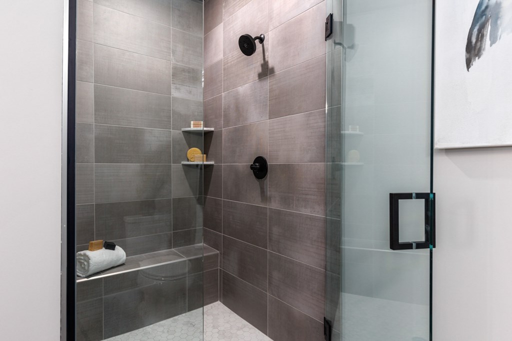 Modern bathroom with a glass shower door and grey tiles at Encore at West Valley, White Lake, 48386