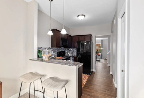 a kitchen with a counter and a bar with two stools