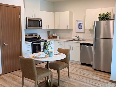 A modern kitchen with a dining table set for two.