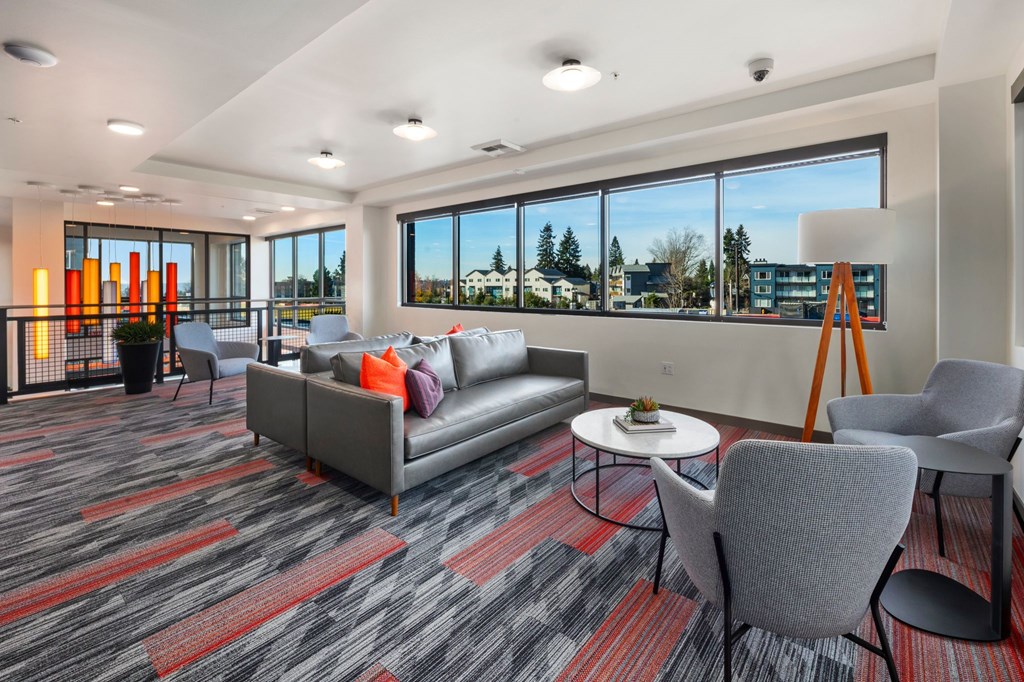 A modern waiting room with grey and red carpeting and comfortable seating.