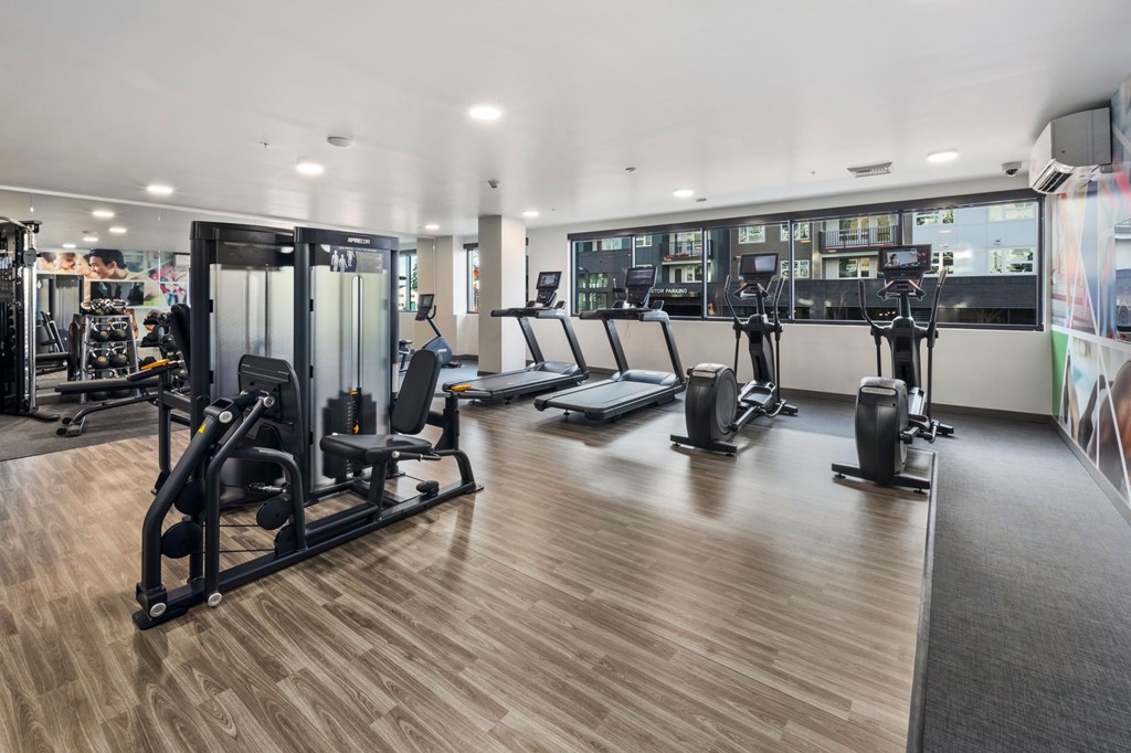 A gym with a variety of equipment including treadmills, weights, and exercise machines.