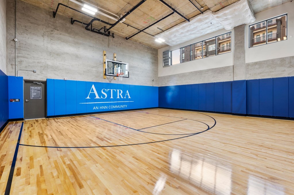 A basketball court with a blue wall and a sign that says "Astra".