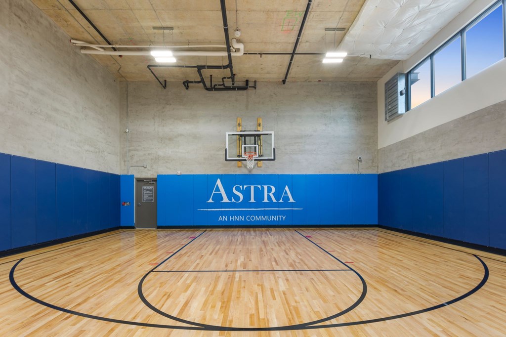 A basketball court with a blue wall and a sign that says "Astra".