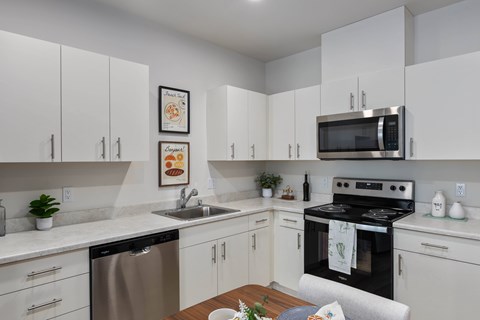 A modern kitchen with white cabinets and stainless steel appliances.