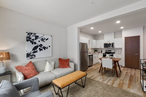 A modern living room with a grey couch, a wooden bench, and a painting on the wall.