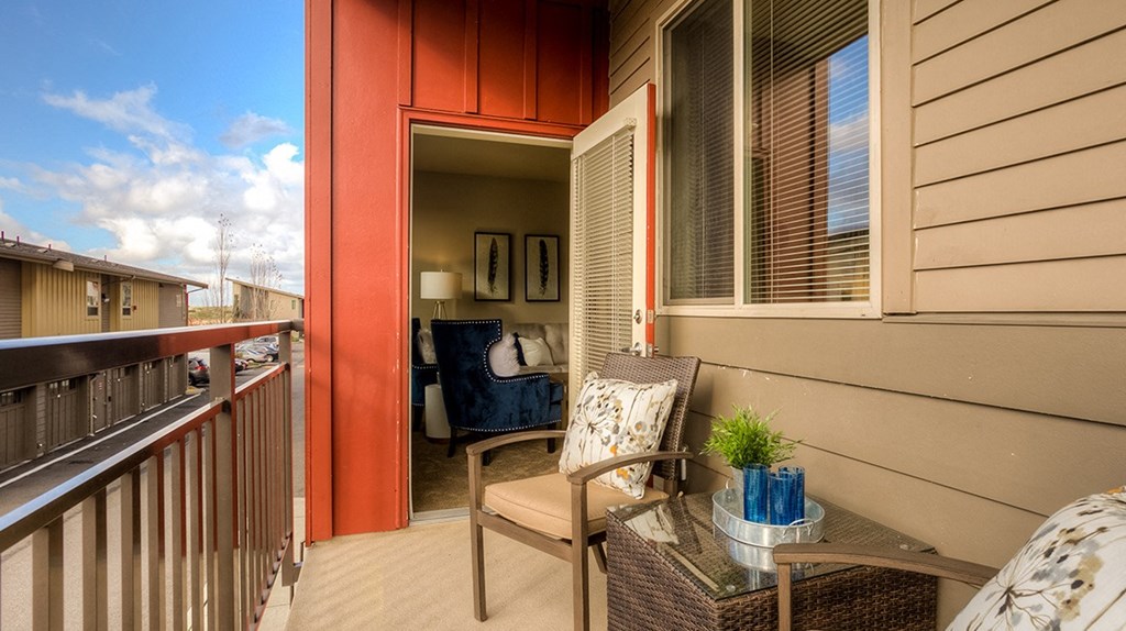 a balcony with a chair and a table and a door to a living room