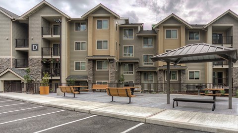 an empty parking lot with benches in front of an apartment building